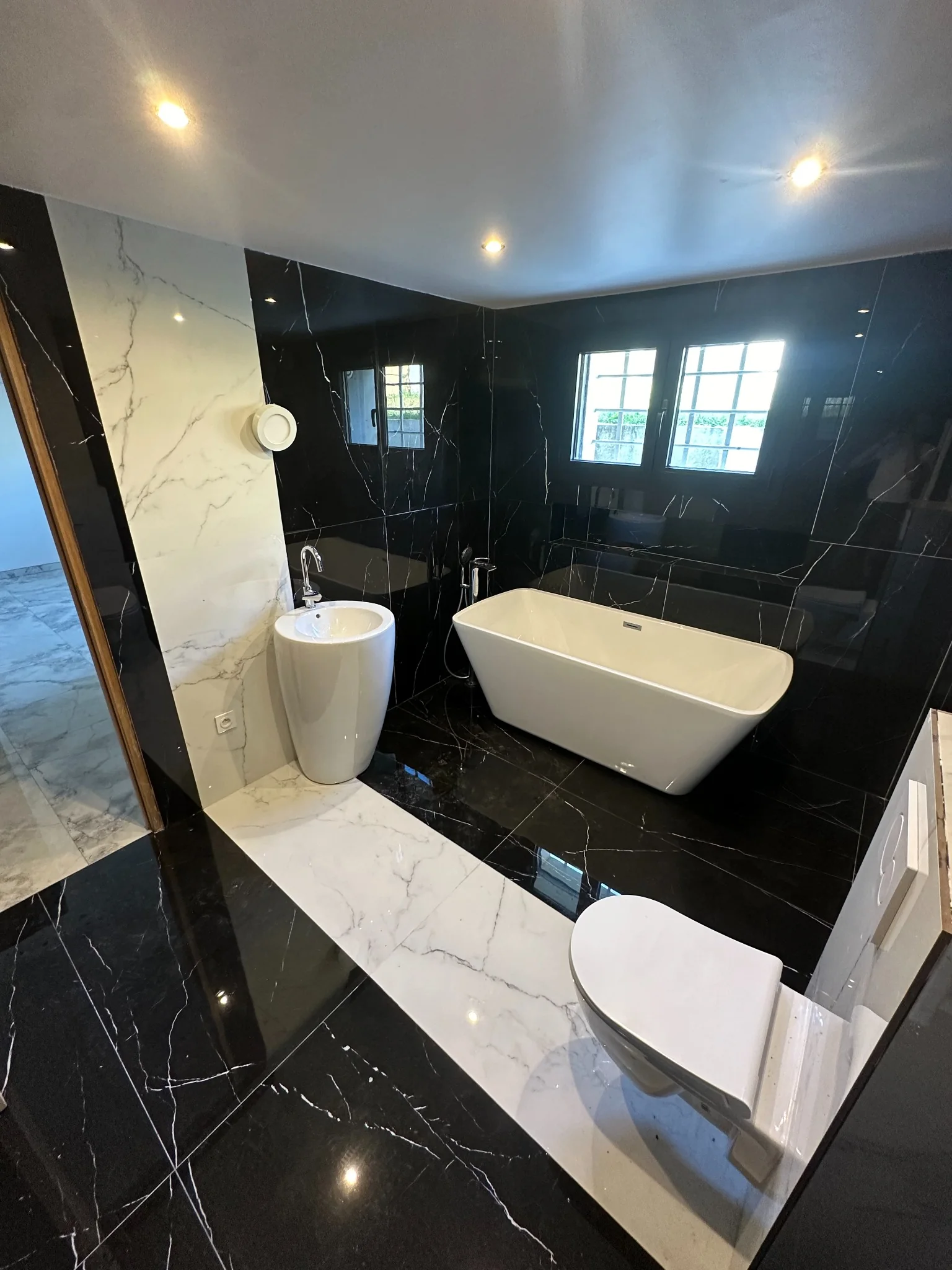 Réalisation Design & Rénovation : salle de bains noire et blanche avec baignoire îlot