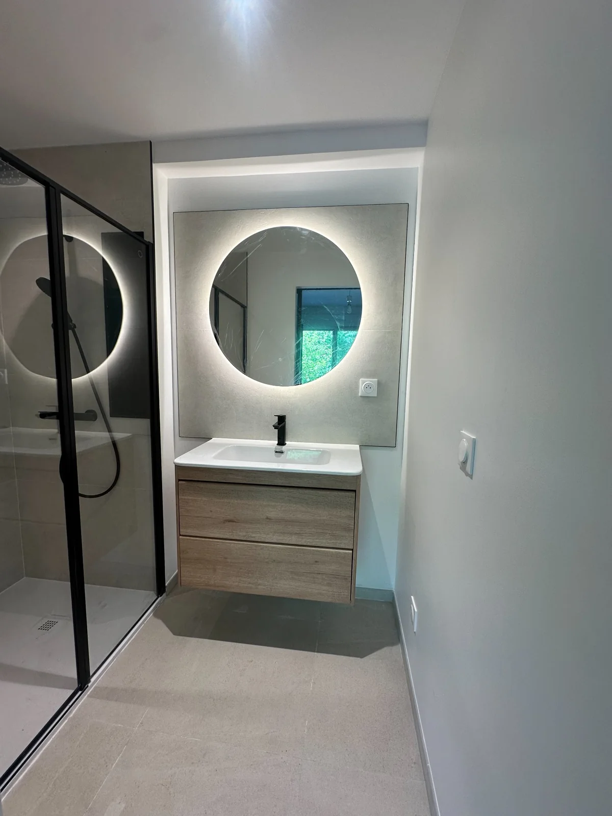 Réalisation Design & Rénovation : douche vitrée noire, meuble suspendu et miroir rond